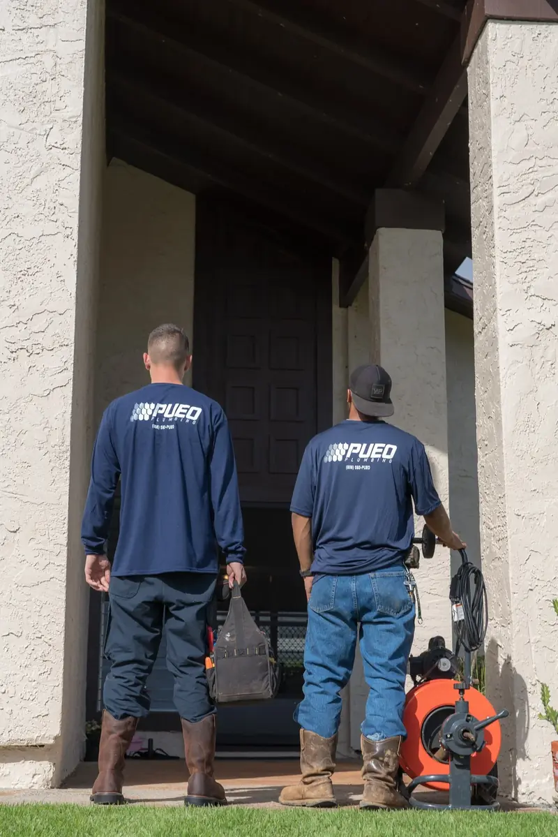 Two Pueo Plumbing technicians arriving at a customer home with their equipment